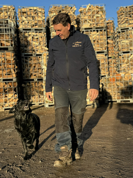 Koen tussen stapels brandhout
